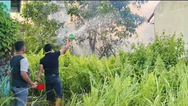 Polisi dan warga di Kampar, Riau memadamkan api yang nyaris merambat ke perumahan, Minggu (20/7/2025).