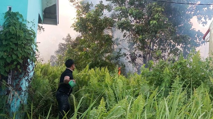 Polisi dan warga di Kampar, Riau memadamkan api yang nyaris merambat ke perumahan, Minggu (20/7/2025).