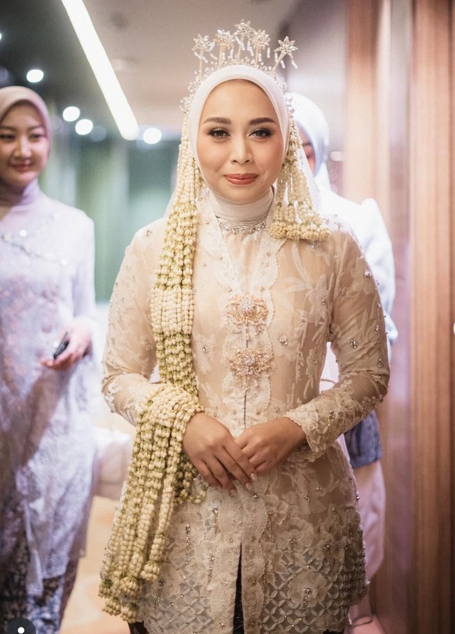 Gaya hijab Putri Karlina ditata oleh @jatupurwanti, yang mengombinasikan hijab modern dengan sentuhan tradisional. Tak ketinggalan, untaian melati panjang menghiasi sisi kepala, menambah kesan sakral khas pengantin Sunda. Foto: Instagram/@putri.karlina14