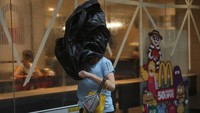 Seorang wanita terekam tengah berjalan menantang angin kencang saat Topan Wipha mulai mendekat ke wilayah Hong Kong, Minggu (20/7). REUTERS/Tyrone Siu