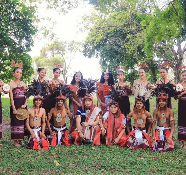 Mereka mengenakan tais, kain tenun khas Timor Leste yang digunakan dalam upacara adat. KD dan keluarganya juga tampak berpose bersama masyarakat di sana. Foto: Instagram/@krisdayantilemos