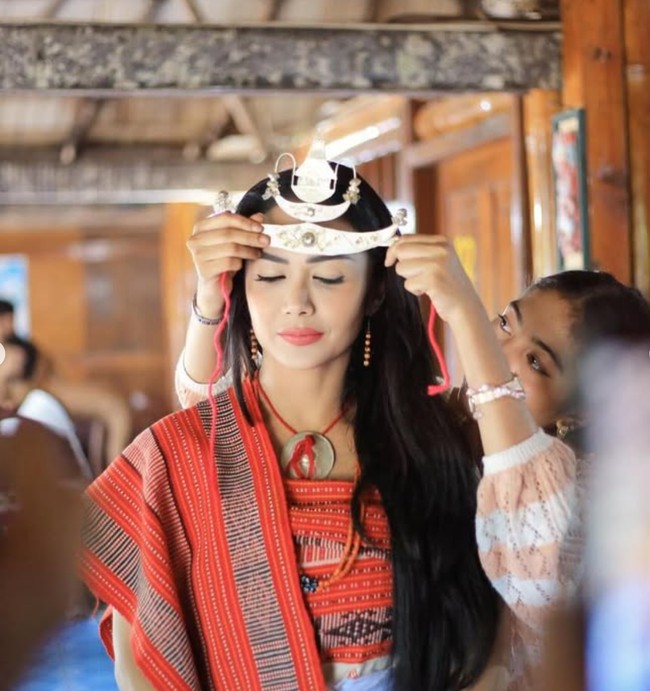 Dalam salah satu foto, Krisdayanti tampak sedang dipasangkan mahkota logam di atas kepalanya. Mahkota tersebut memiliki bentuk unik menyerupai bulan sabit. Foto: Instagram/@krisdayantilemos