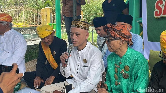 Muhammad Fuad Riyadi alias Fuad Plered (Baju putih) saat menjalani sanksi adat atas dugaan penghinaan terhadap pendiri Alkhairaat di rumah adat Banua Oge Souraja, Kota Palu, Minggu (20/7/2025).
