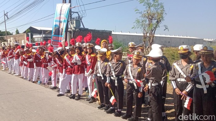 Para siswa bersiap menyambut presiden Prabowo Subianto di jalan Pakis Wonosari, Klaten, Senin (21/7/2025).
