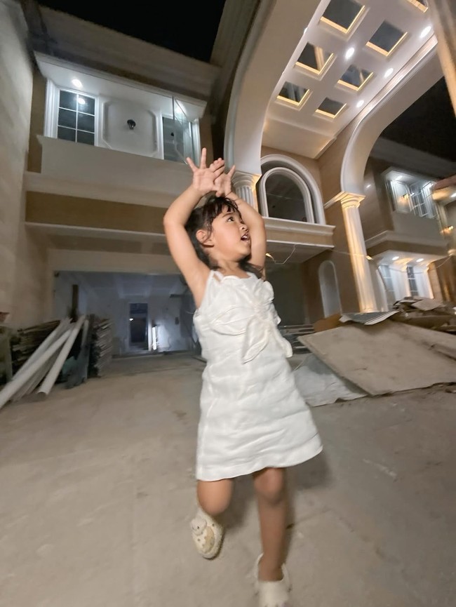 Ibunda Ricis pun tak kalah bahagia melihat pencapaian putrinya. Dalam beberapa dokumentasi yang dibagikan, ia tampak tersenyum bangga berdiri di depan rumah baru yang kelak akan ditempati Ricis dan putrinya, Moana. (Foto: Instagram/@riaricis1975)