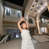 Ibunda Ricis pun tak kalah bahagia melihat pencapaian putrinya. Dalam beberapa dokumentasi yang dibagikan, ia tampak tersenyum bangga berdiri di depan rumah baru yang kelak akan ditempati Ricis dan putrinya, Moana. (Foto: Instagram/@riaricis1975)