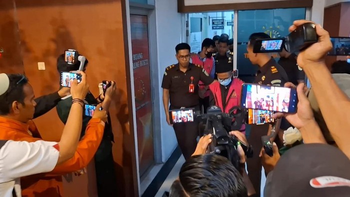 Tiga tersangka dugaan korupsi proyek rehabilitasi dan renovasi 25 sekolah di Kota Kupang dan Kabupaten Kupang, NTT, saat digiring ke mobil tahanan, Senin (21/7/2025). (Yufengki Bria/detikBali)