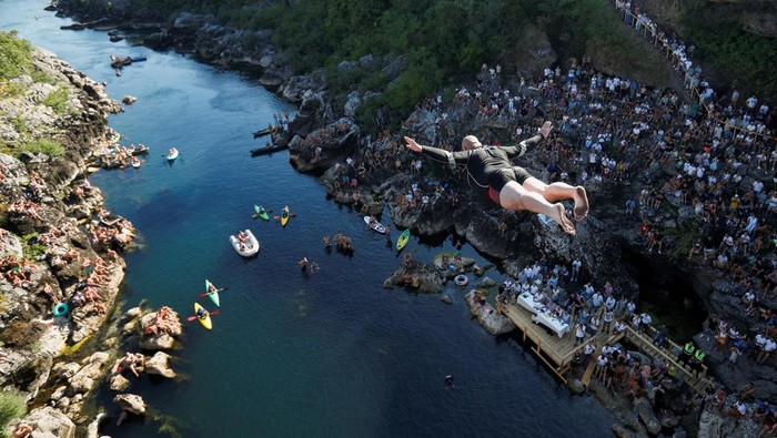 Tradisi Uji Nyali Lompat dari Jembatan 23 Meter di Montenegro An athlete jumps from 23-meter-high Vizier bridge over Moraca river after 15 years of pause in traditional high diving competition in Podgorica, Montenegro, July 19, 2025. REUTERS/Stevo Vasiljevic REFILE - CORRECTING YEAR FROM