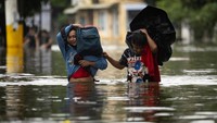Warga Cainta berjalan melewati genangan air usai banjir monsoon melanda wilayah mereka. Proses evakuasi terus dilakukan sepanjang hari. REUTERS/Eloisa Lopez