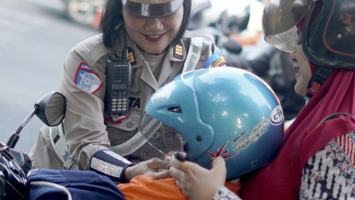 Polisi di Surabaya bagikan helm untuk anak yang dibonceng orang tuanya.