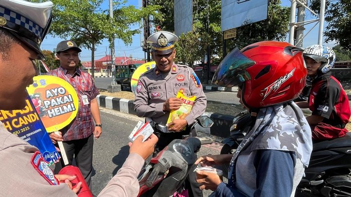 Satlantas Polres Purbalingga saat membagikan minyak goreng kepada pengendara yang tertib berlalu lintas di simpang empat patung Jenderal Soedirman, Selasa (22/7/2025).