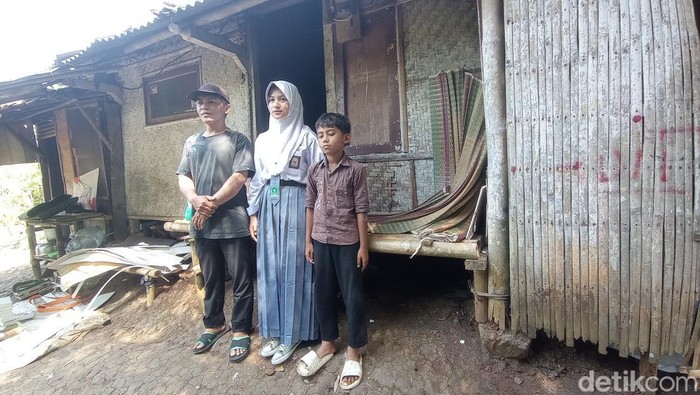 Sella dan kakaknya berfoto di depan rumahnya.