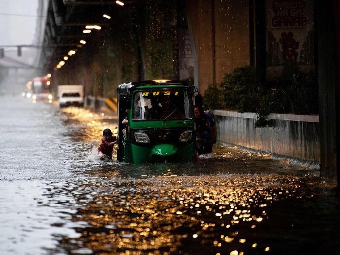 A boy helping to push a vehicle through a flooded street in Philippine capital Manila on July 22, after heavy rains caused floods.

PHOTO: AFP