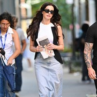 Gaya pertama menunjukkan Anne mengenakan rok denim panjang dari Agolde yang dipadukan tank top putih dan rompi hitam. Jika dulu Andy identik dengan stiletto di kantor, kini ia tampil lebih casual dengan sandal dari Chanel. Tidak membawa tas tangan, Anne justru menggenggam koran layaknya simbol semangat jurnalisme klasik di tengah era digital. Foto: GC Images/James Devaney