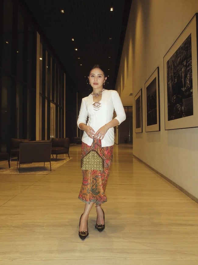 Prilly Latuconsina memadukan kebaya kutu baru putih polos yang timeless dengan kain batik motif parang warna merah dan emas. Dilengkapi aksesoris klasik seperti bros dan clutch etnik, tampilan ini memberikan kesan formal nan elegan. Foto: Instagram/@prillylatuconsina96
