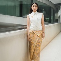 Dian Sastrowardoyo menampilkan kebaya modern yang sleek dan tegas. Potongan sleeveless dengan kerah kemeja dan siluet asimetris menciptakan nuansa kontemporer. Kain batik sogan bernuansa kuning emas menjadi pelengkap yang tetap menjaga akar tradisional dalam balutan modernitas. Foto: Instagram/@theraldisastr