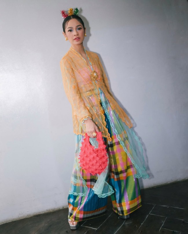 Andien selalu sukses menampilkan gaya berbeda pada busana tradisional. Kali ini, pelantun lagu ‘Gemintang’ itu memancarkan kesan ceria dengan kebaya oranye transparan berbordir yang dipadukan dengan kain tenun kotak warna-warni khas Betawi. Foto: Instagram/@andien