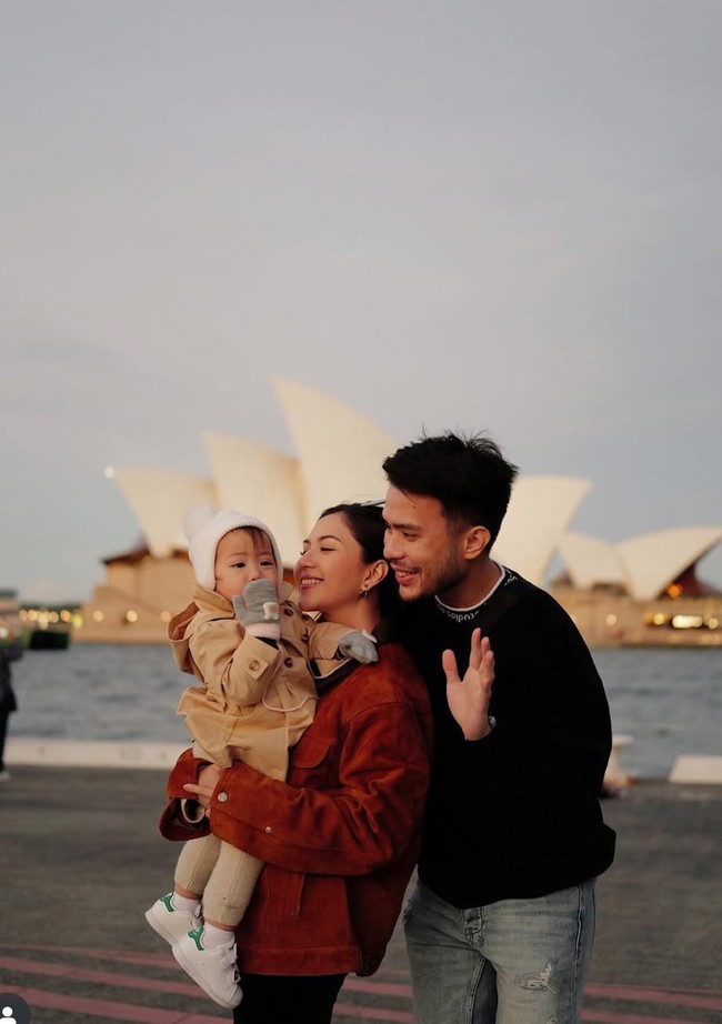 Jessica Mila terlihat berpose bahagia bersama suami dan buah hatinya dengan latar belakang Sydney Opera House. Momen ini memperlihatkan kehangatan keluarga kecil mereka saat menikmati senja di tepi laut. Foto: Instagram/@jscmila
