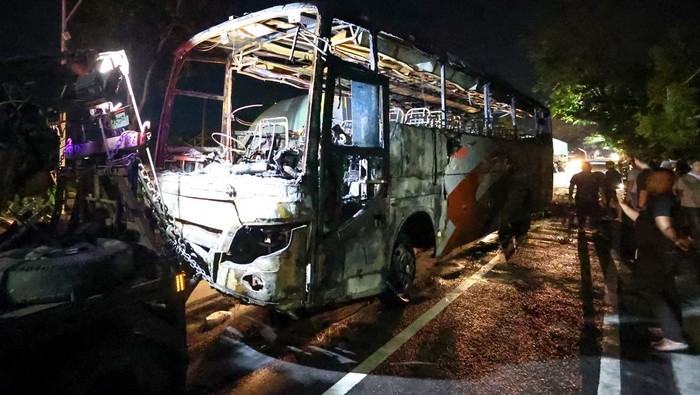 Kecelakaan Bus di Nganjuk Picu Kebakaran dan Korban Jiwa Petugas kepolisian mengamati kondisi bangkai bus pascakebakaran di ruas jalan nasional Nganjuk, Jawa Timur, Selasa (22/7/2025). Kecelakaan lalu lintas yang melibatkan bus antar kota dalam provinsi (AKDP) rute Surabaya-Ponorogo dengan sepeda motor itu menyebabkan bus terbakar dan satu orang meninggal dunia. ANTARA FOTO/Muhammad Mada/nz