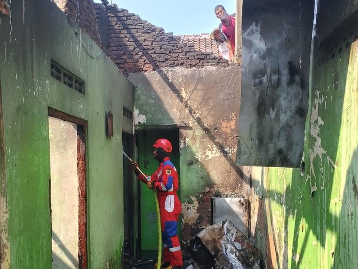 Petugas memadamkan api yang membakar dua rumah di Desa Karangsoka, Kecamatan Kembaran, Kabupaten Banyumas, Rabu (23/7/2025).
