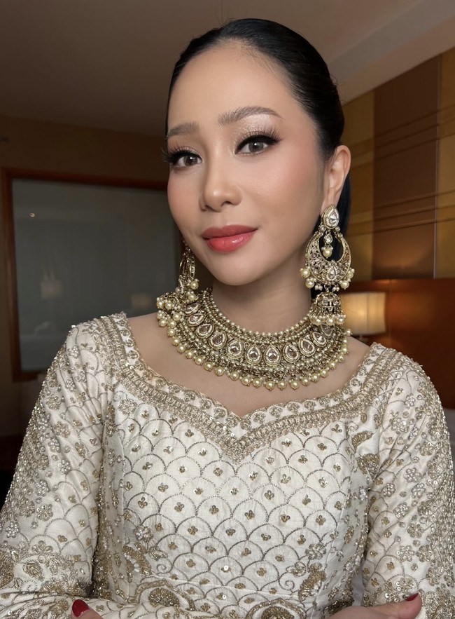 Riasan wajah Bunga tampil sempurna dengan complexion matte bercahaya, mata tegas dengan eyeliner winged, dan lipstik warna coral-pink. Rambutnya ditata sleek ke belakang, membuat perhiasan di area wajah tampak maksimal. Foto: dok. Instagram @bungazainal05