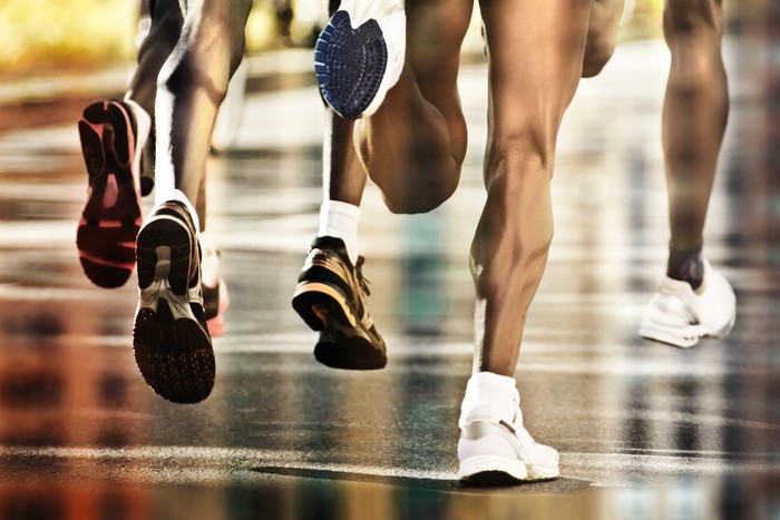 Runners on wet ground with city reflection
