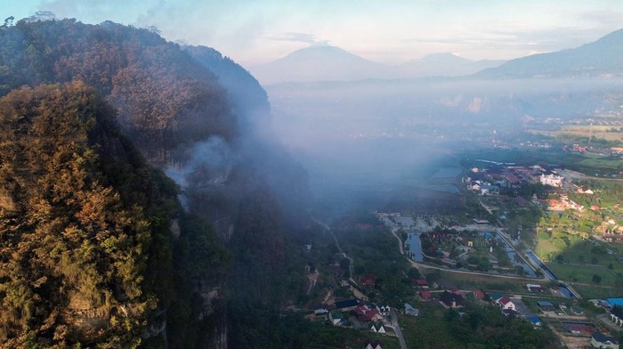 Foto udara petugas berusaha memadamkan kebakaran hutan di Lembah Harau, Limapuluh Kota, Sumatera Barat, Kamis (24//7/2025). Pemkab Limapuluh Kota telah menetapkan masa tanggap darurat bencana karhutla mula 17  hingga 30 Juli 2025 karena dampaknya meluas di kabupaten itu.  ANTARA FOTO/Iggoy el Fitra