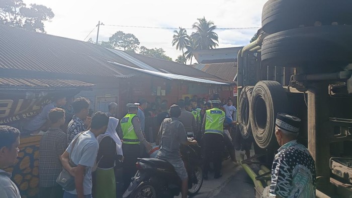 Truk tronton yang terbalik dan menabrak mobil.