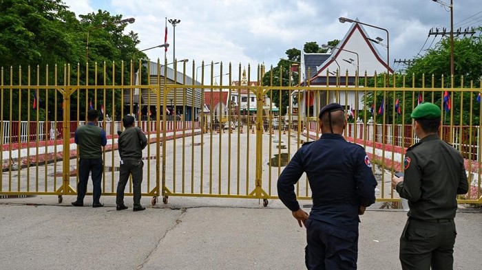 Cambodian police officials stand next to the closed gate at Poipet International border checkpoint between Cambodia-Thailand, at Poipet town in Banteay Meanchey province on June 24, 2025. Thailands army closed border crossings with Cambodia in six provinces on June 23 to all vehicles and foot passengers except students and people seeking medical treatment, as a territorial row between the neighbours rages. (Photo by TANG CHHIN Sothy / AFP)