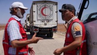 Para pekerja Bulan Sabit Merah Arab Suriah berdiri di samping kendaraan pengangkut bantuan saat mereka menuju Sweida. Gencatan senjata diberlakukan pada Minggu (20/7) ketika pasukan keamanan Kementerian Dalam Negeri dikerahkan di pinggiran Sweida. Menteri Dalam Negeri Anas Khattab mengatakan pada hari Minggu bahwa gencatan senjata akan memungkinkan pembebasan sandera dan tahanan yang ditahan oleh kedua belah pihak. Foto: REUTERS/Karam al-Masri