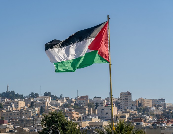 The large Palestinian flag (flag of Palestine) is waiving above the city.