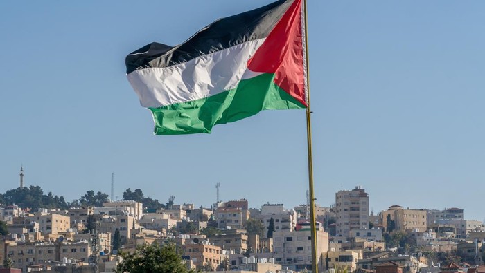 The large Palestinian flag (flag of Palestine) is waiving above the city.