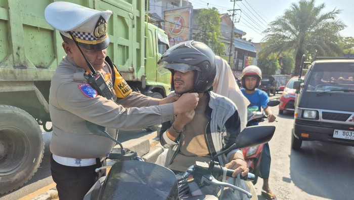 Polisi di Surabaya Utara saat melakukan tindakan teguran simpatik kepada pengendara motor yang helm-nya tidak dikancingkan.