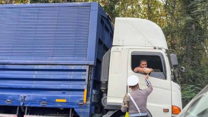 Anggota Satlantas Polres Situbondo membagikan makanan ke pengendara truk yang terjebak di jalan pantura hutan Baluran