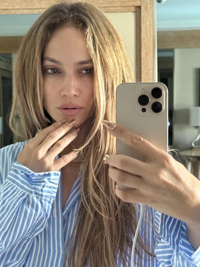 Dalam unggahan di Instagram, Rabu (24/7/2025), Jennifer Lopez terlihat mengenakan kemeja bergaris biru-putih sambil berpose di depan cermin. Tanpa polesan makeup, ia memamerkan kecantikan alaminya yang tetap bercahaya meski sudah memasuki usia setengah abad lebih. Penampilan tersebut sekaligus menjadi promosi tersirat untuk lini perawatan kulit miliknya, JLo Beauty. (Foto: Instagram/@jlo)