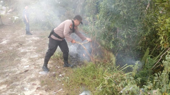 Polisi dan Damkar sigap memadamkan api yang membakar ilalang di Jalan Sudirman Ujung, Jumat (25/7/2025).
