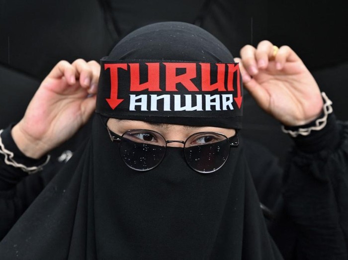 A protester wears a headband with the slogan that reads Step down Anwar as she gathers near Merdeka Square during a protest against Malaysias Prime Minister Anwar Ibrahim in Kuala Lumpur on July 26, 2025. Several thousand Malaysians took to the capitals streets to protest growing public discontent over rising living costs and a perceived lack of reform by Prime Minister Anwar Ibrahims unity government. (Photo by Mohd RASFAN / AFP)