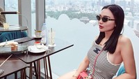 Tampil dengan pakaian kasual tapi tetap modis, Wika berpose saat menikmati rangkai afternoon tea dengan pemandangan kota di sore hari. Foto: Instagram @wikasalim