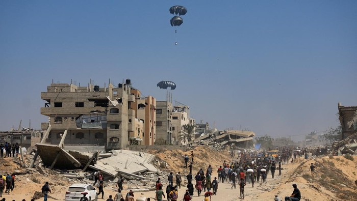 Langit Gaza Dipenuhi Parasut Bantuan Kemanusiaan An aircraft drops humanitarian aid packages over the Gaza Strip, as seen from Israel, July 27 2025. REUTERS/Amir Cohen BEST QUALITY AVAILABLE