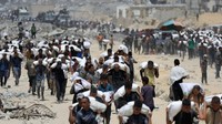 Warga di Beit Lahia, Gaza utara, memanggul paket bantuan yang dijatuhkan dari udara dan berhasil masuk melalui jalur Israel, Sabtu (27/7/2025). Mereka segera berebut bantuan tersebut, yang berisi makanan dan kebutuhan dasar. REUTERS/Dawoud Abu Alkas