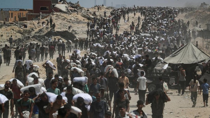 Palestinians carry aid supplies that entered Gaza through Israel, in Beit Lahia, northern Gaza Strip, July 27, 2025. REUTERS/Mahmoud Issa