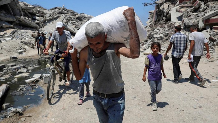 Palestinians carry aid supplies that entered Gaza through Israel, in Beit Lahia, northern Gaza Strip, July 27, 2025. REUTERS/Mahmoud Issa