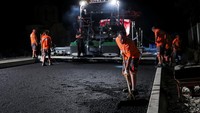 Pemerintah baru-baru ini memerintahkan penutupan pekerjaan jalan selama periode panas ekstrem. Pekerjaan perbaikan jalan pun dipindah ke malam hari. Foto: REUTERS/Valdrin Xhemaj