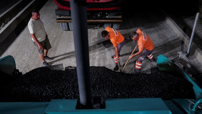 Kosovo Mendidih, Pekerja Jalan Berpacu dengan Waktu dan Suhu Workers lay asphalt at night to avoid the daytime heat wave, on a street in the town of Rahovec, Kosovo July 23, 2025. REUTERS/Valdrin Xhemaj