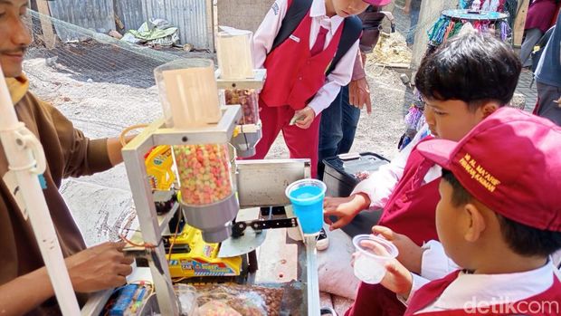 Penjual es, Anang Ariadi Kurniawan (30) melayani pembeli menggunakan robot di Parakan, Temanggung, Senin (28/7/2025).