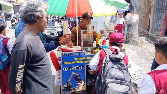 Penjual es, Anang Ariadi Kurniawan (30) melayani pembeli menggunakan robot di Parakan, Temanggung, Senin (28/7/2025).