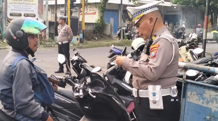 Salah satu anggota Satlantas Polres Lamongan saat memeriksa kelengkapan kendaraan seorang pengendara motor.