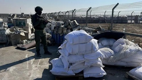 An Israeli soldier stands guard next to humanitarian aid at the Kerem Shalom crossing between southern Israel and the Gaza Strip on July 27, 2025. (AFP)