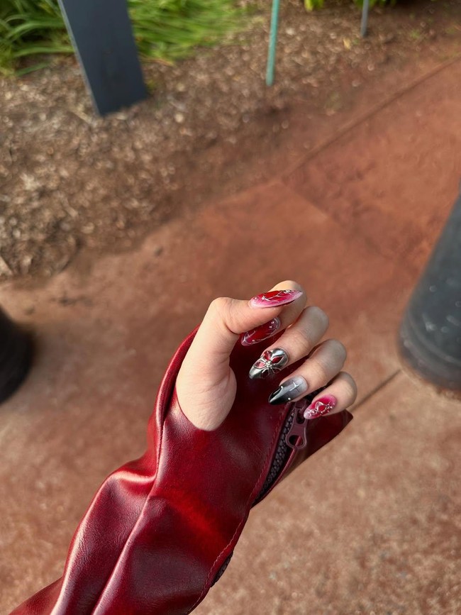 Detail gaya yang tak kalah mencuri perhatian adalah nail art bertema edgy-glam dengan dominasi warna merah, hitam, dan chrome, dihiasi motif silang dan aksen 3D berbentuk bunga metalik. Foto: Instagram/@tiaraandini
