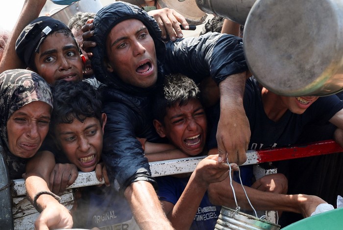Palestinians react as they wait to receive food from a charity kitchen, amid a hunger crisis, in Gaza City, July 26, 2025. REUTERS/Mahmoud Issa     TPX IMAGES OF THE DAY